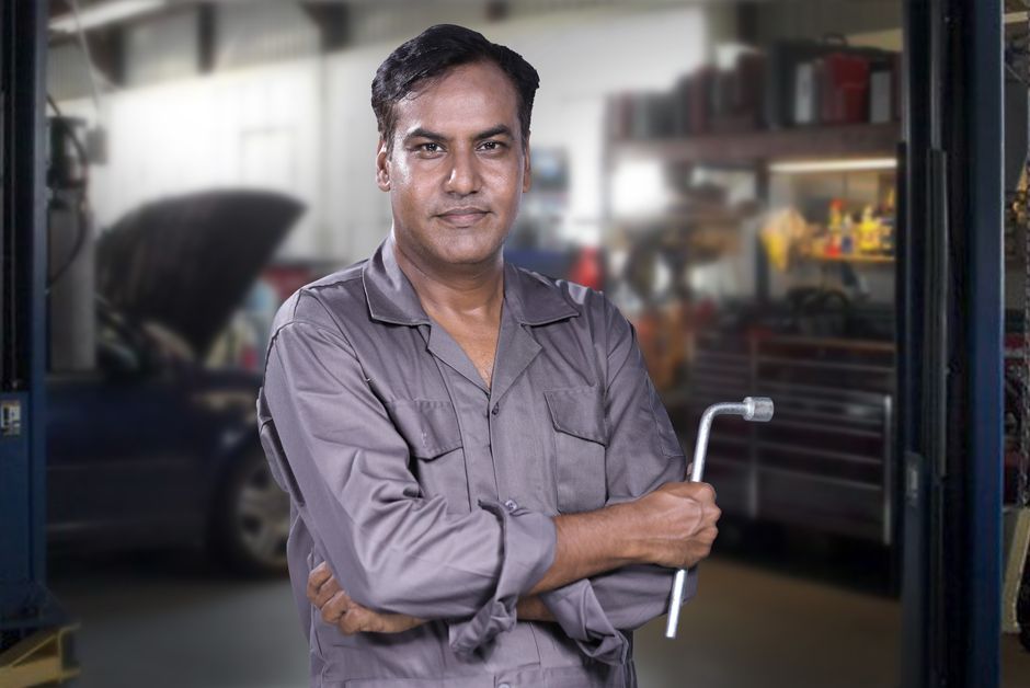 Smiling auto mechanic standing proudly in the shop